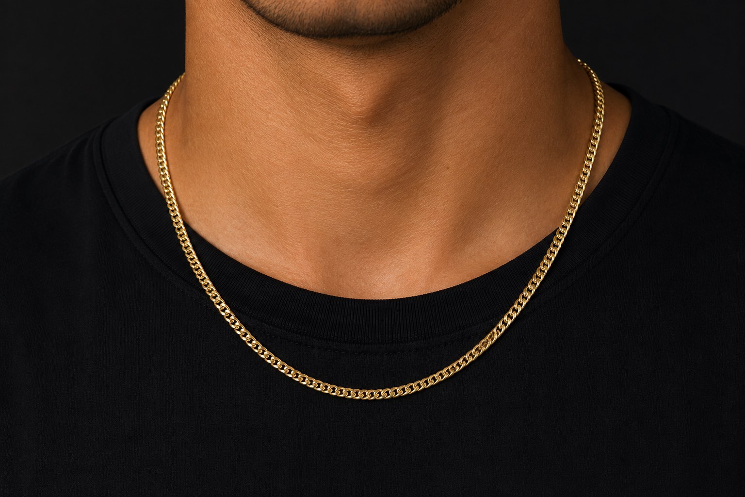 A man in a black tee wearing the 5mm solid gold Cuban link chain, photographed against a near-black ground.